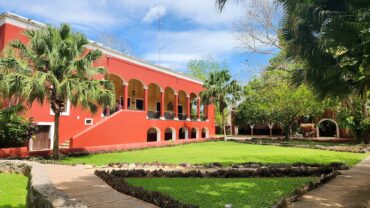 Casa principal color rojo de la Hacienda Sotuta de Peón con jardines y palmeras, cerca de Mérida, Yucatán