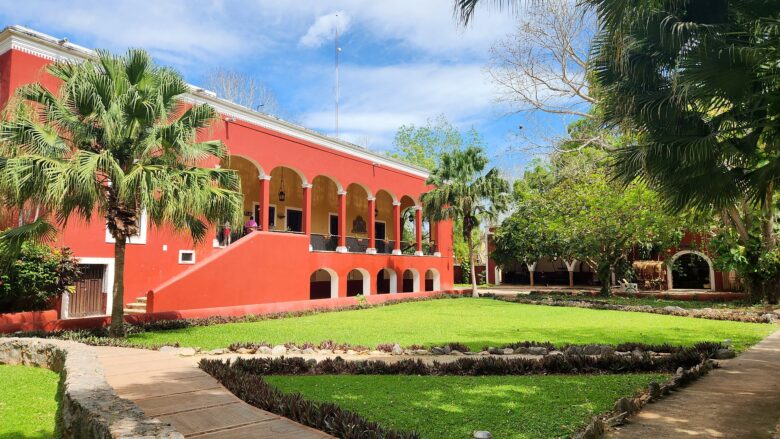 Casa principal color rojo de la Hacienda Sotuta de Peón con jardines y palmeras, cerca de Mérida, Yucatán