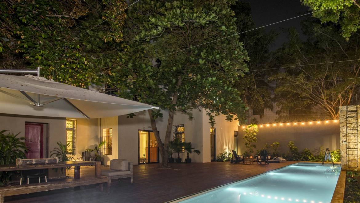 Patio con alberca de Casa Tuut iluminado de noche sobre Paseo de Montejo, Mérida